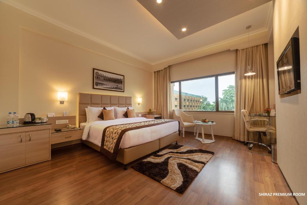 a hotel room with a bed and a large window at Hotel Clarks Shiraz in Agra