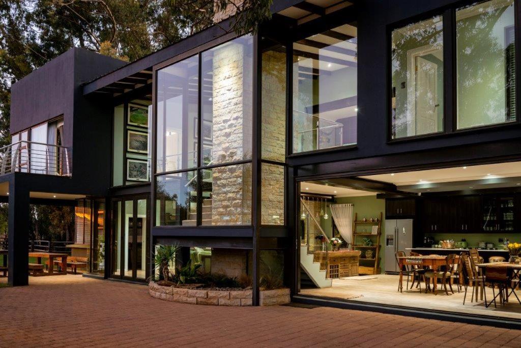 a house with large glass windows and a patio at Middelwater Farm Hotel in Bloemfontein