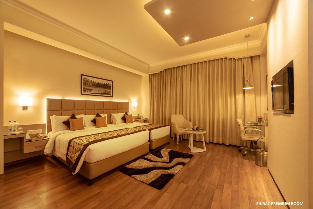 a hotel room with a large bed and a desk at Hotel Clarks Shiraz in Agra