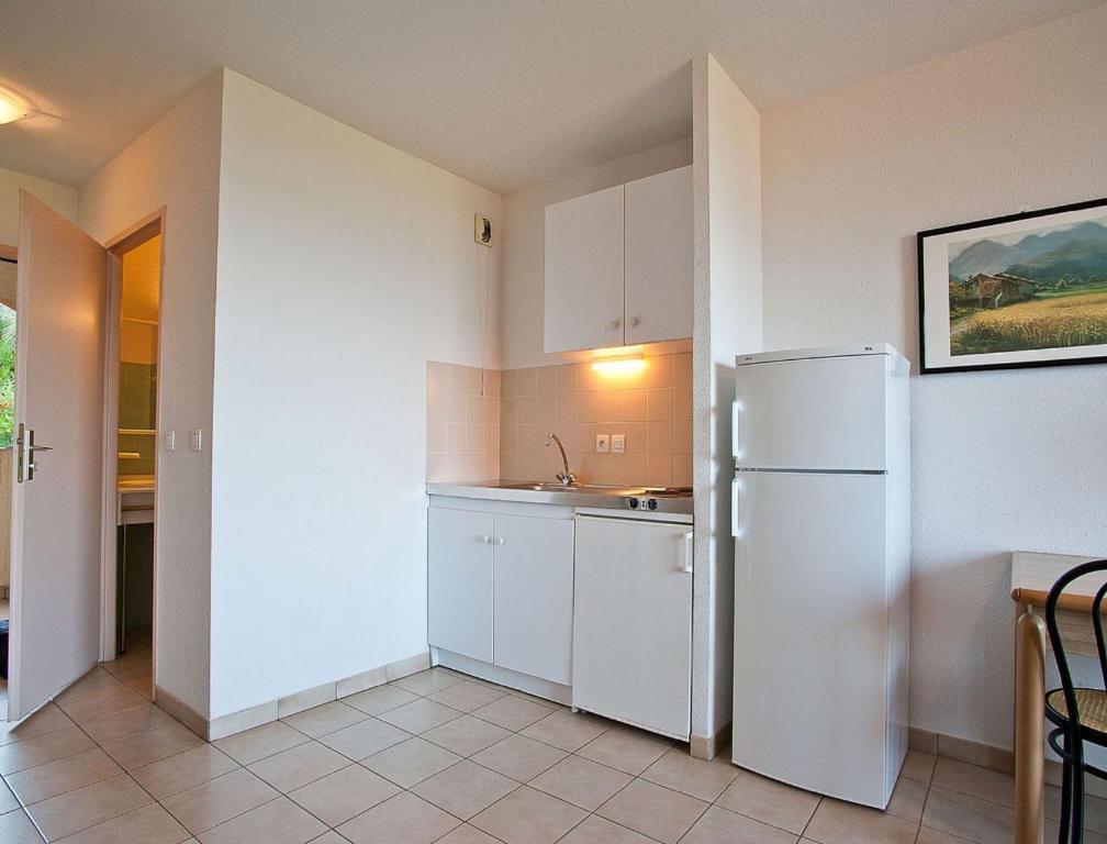 a kitchen with white cabinets and a refrigerator at Résidence Suarella in Saint-Florent