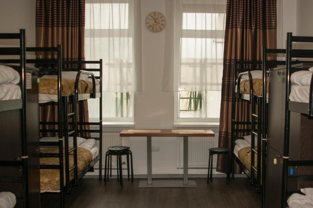 Cette chambre dispose de lits superposés, d'une table et d'une horloge. dans l'établissement Art Galery Hostel, à Lviv