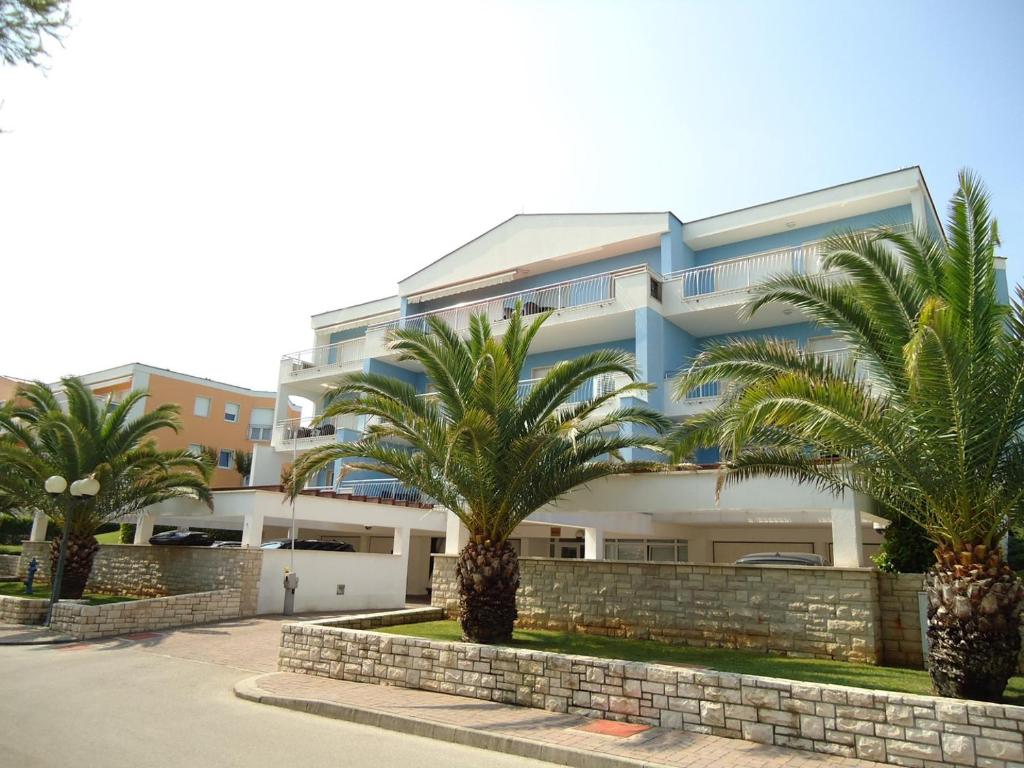 a building with palm trees in front of it at Luxury apartment Pelargonija in Monterosso Resort in Savudrija