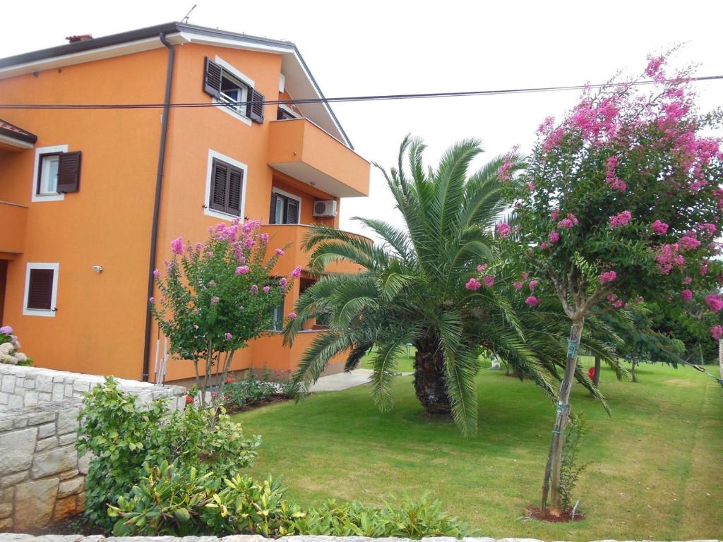 an orange building with a palm tree in front of it at Anita's Terrace Apartment in Zambratija