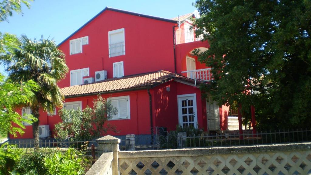 a red house with a fence in front of it at Apartments Branka in Zambratija