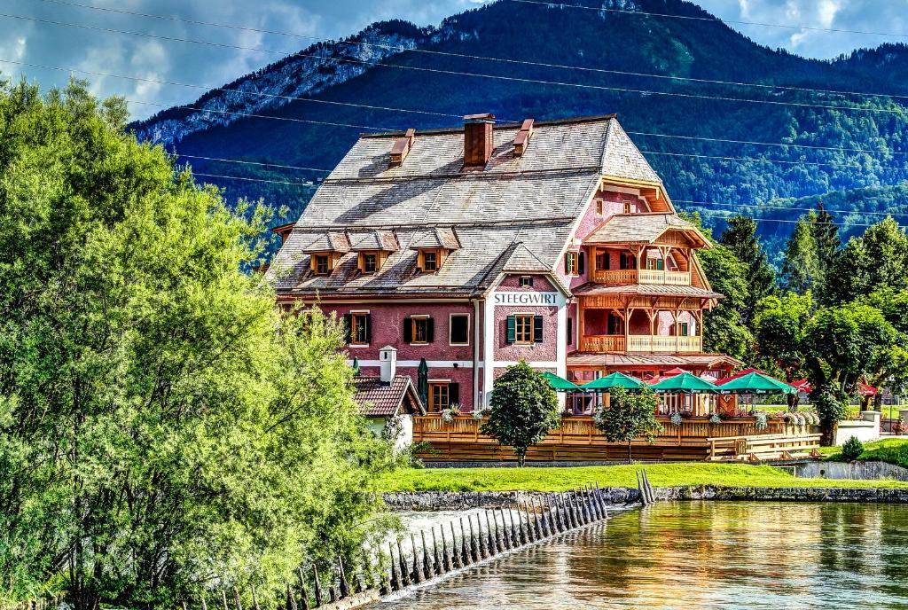 a large house sitting next to a river at Welterbe-Wirtshaus Steegwirt in Bad Goisern
