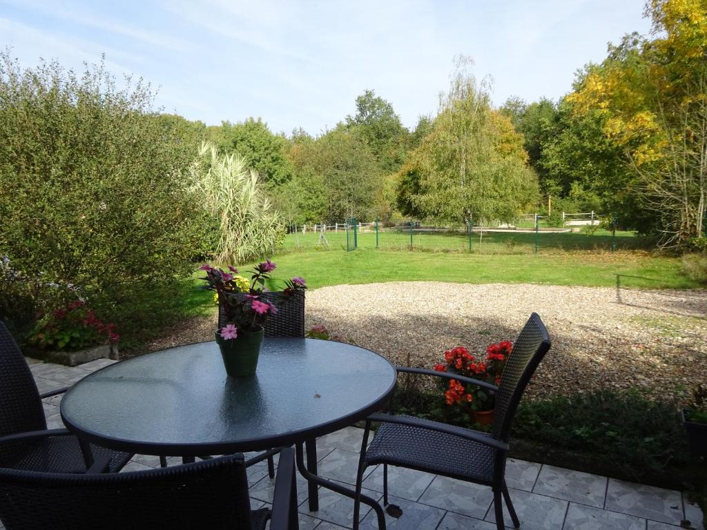una mesa con un jarrón de flores en un patio en Les chaumières du Chêne, en Pouillé