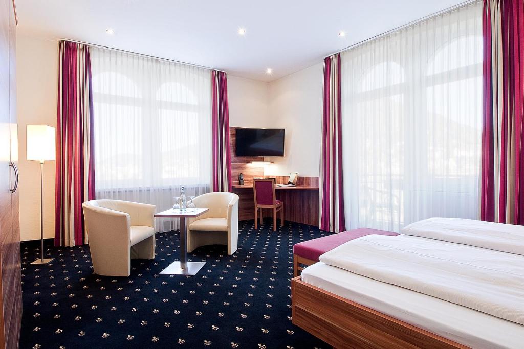 ein Hotelzimmer mit 2 Betten, einem Tisch und Stühlen in der Unterkunft Hotel Panorama in Heidelberg