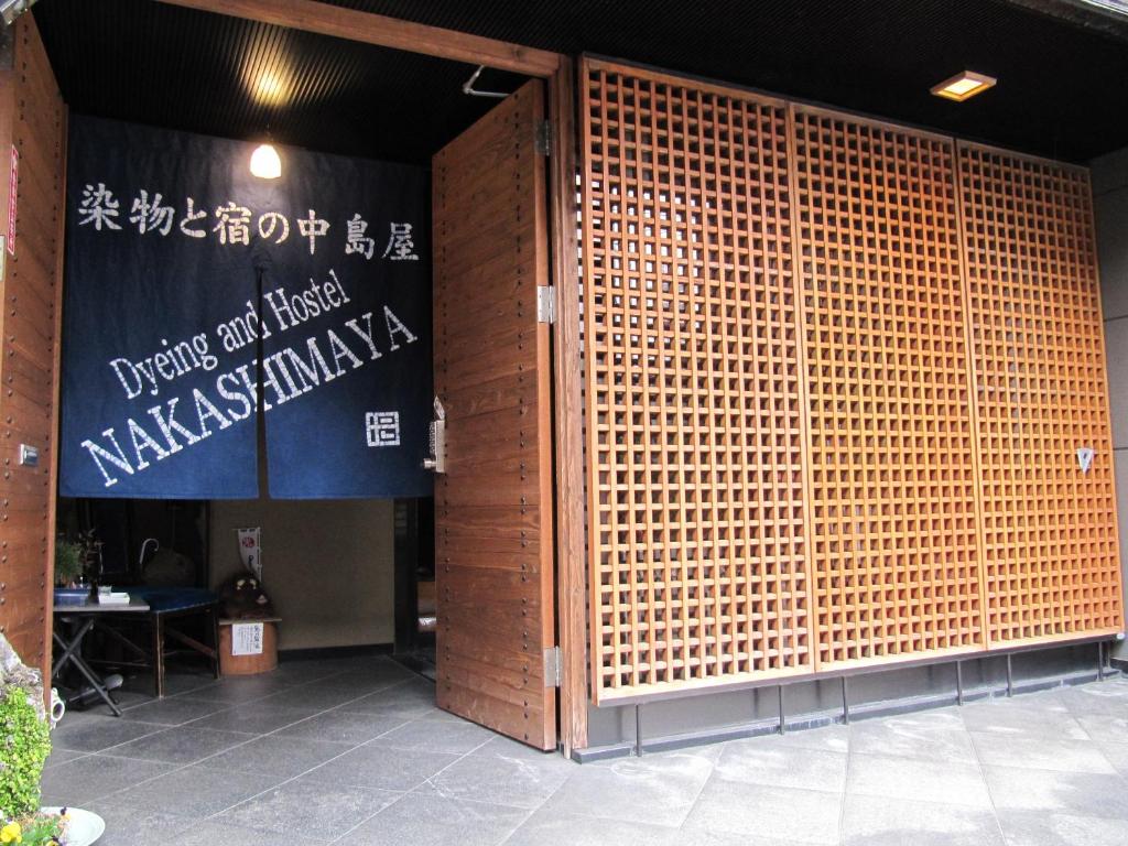 einen Eingang zu einem Gebäude mit einer großen Bambusmauer in der Unterkunft Dyeing and Hostel Nakashimaya - Female Only in Kumamoto