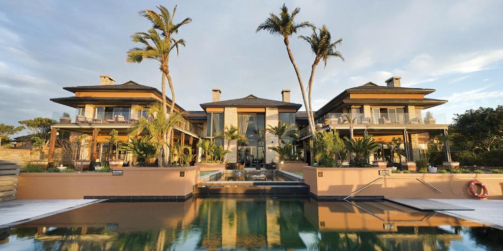 a house with a swimming pool and palm trees at Pezula Nature Retreat in Knysna