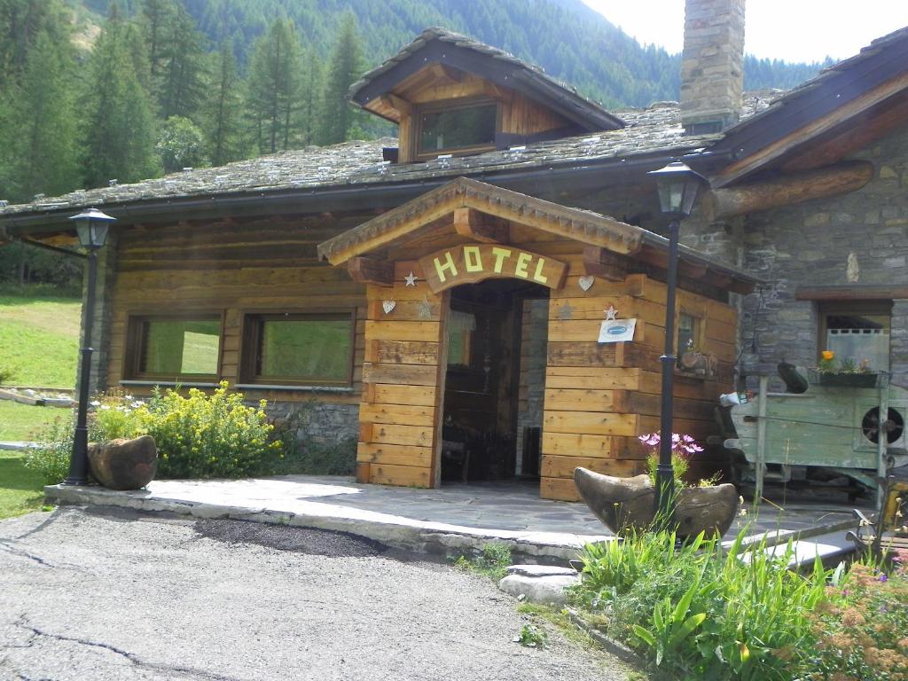 Cabaña de madera con porche y puerta en Hotel Les Granges, en La Thuile