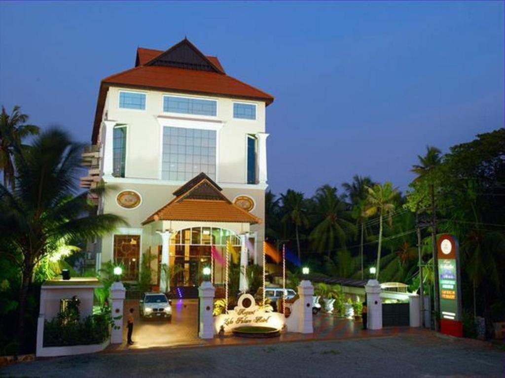 un gran edificio blanco con un coche aparcado delante de él en Regant Lake Palace Hotel, en Nīndakara