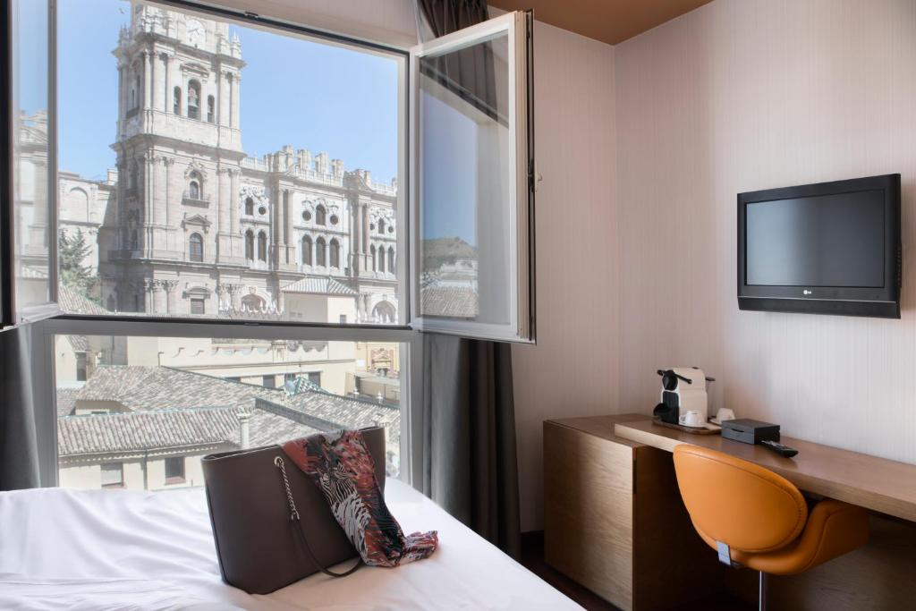 een hotelkamer met uitzicht op een gebouw bij Petit Palace Plaza Málaga in Málaga