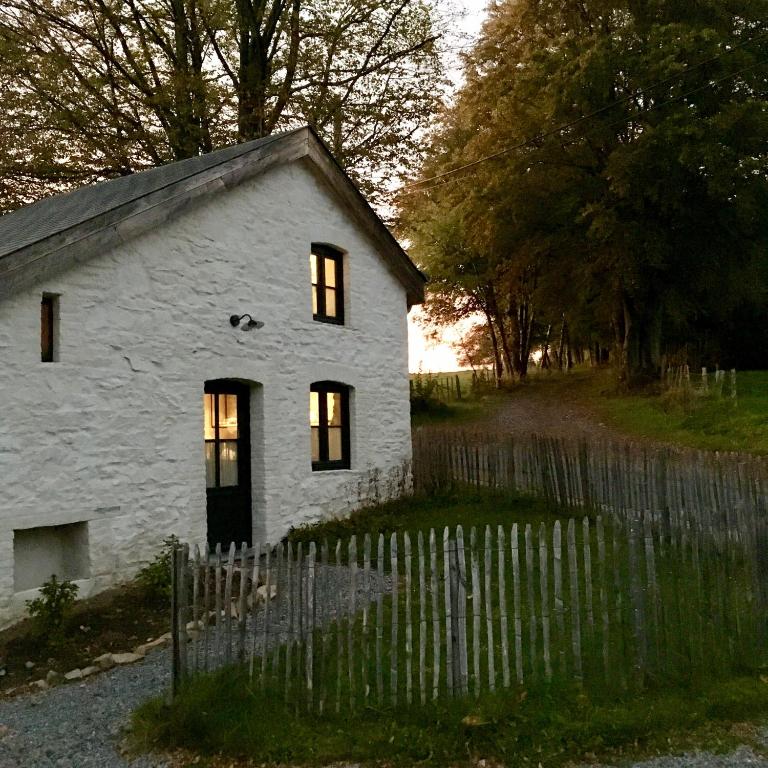 een wit stenen huis met ramen en een hek bij Le Nid in Manhay