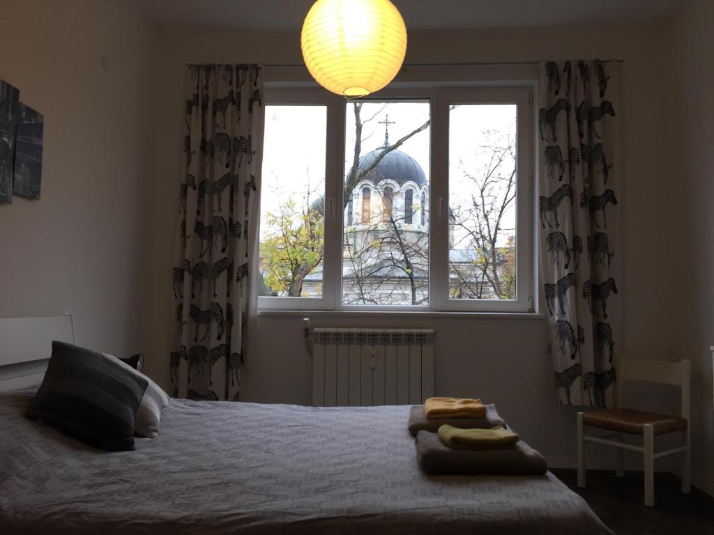 a bedroom with a bed and a large window at Sweet home in the heart of Sofia in Sofia
