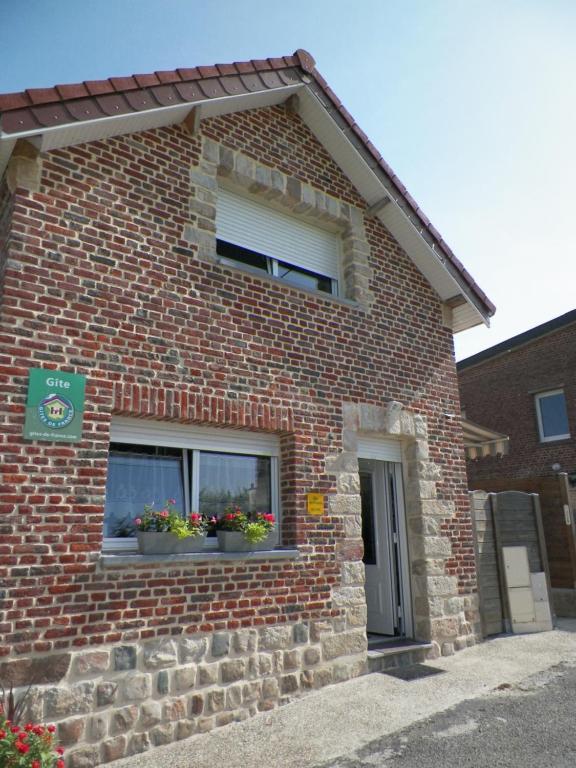 un edificio de ladrillo con dos ventanas con flores. en Gîte les Prairies en Maresches