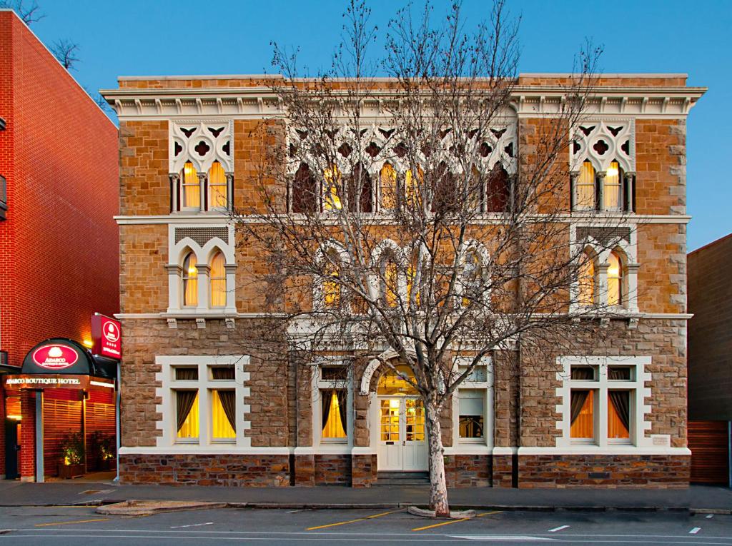 un edificio de ladrillo con un árbol delante de él en Adabco Boutique Hotel Adelaide, en Adelaida