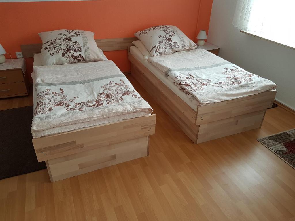 two twin beds in a room with wooden floors at Zimmer Müller in Wesseling