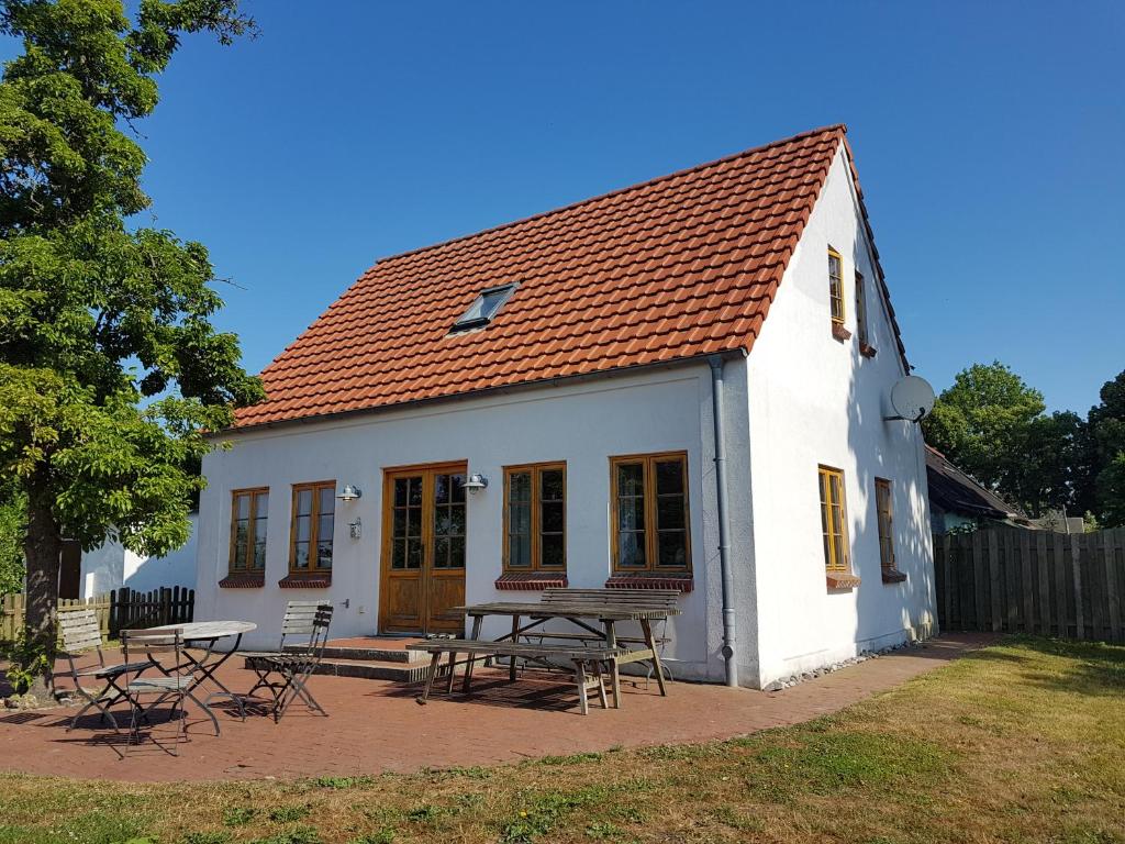 Casa blanca con mesa de picnic y sillas en Authentisches Inselhaus - ideal für Kiter/Surfer/Familien, en Fehmarn
