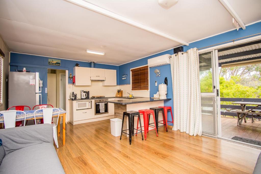 a kitchen and dining room with blue walls and red chairs at The Gee Beach House in Guilderton