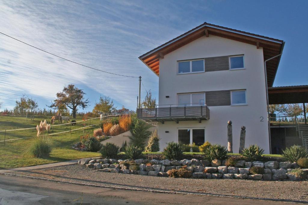 une maison blanche avec un balcon sur une colline dans l'établissement Schmid's Ponyhöfle, à Friedrichshafen