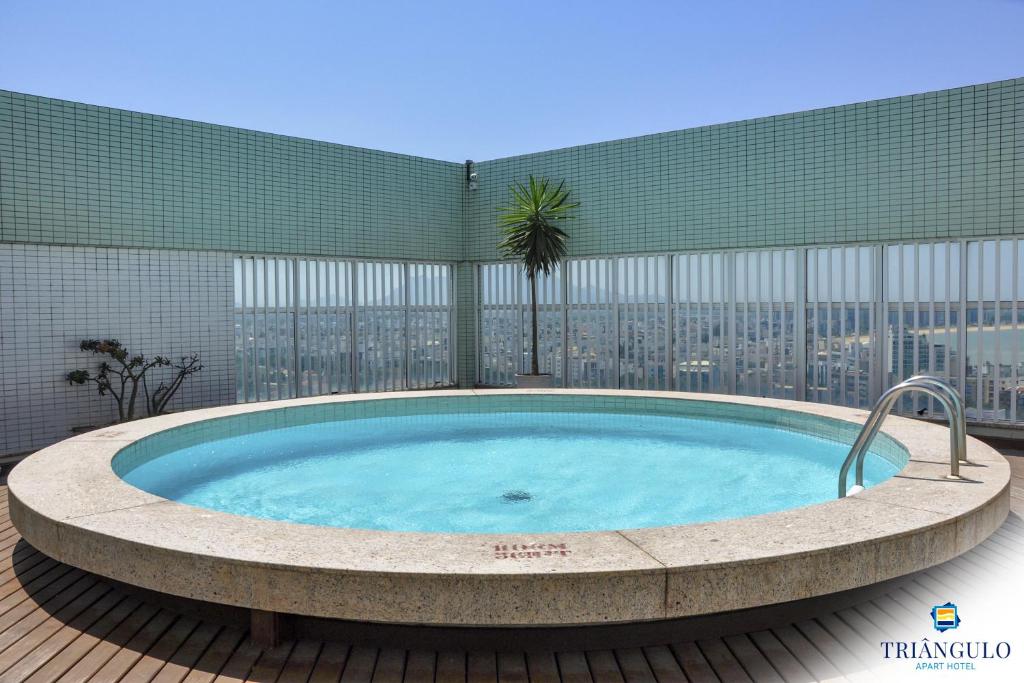 un patio con bañera de hidromasaje y vistas a la ciudad en Triângulo Apart Hotel en Vitória