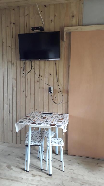 ein weißer Tisch mit zwei Stühlen und einem Fernseher an der Wand in der Unterkunft Residencial Maia in Capão da Canoa