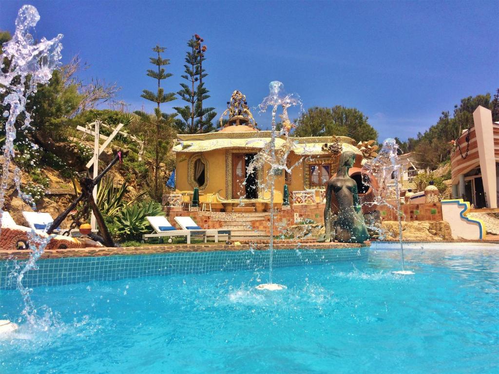 a swimming pool with a fountain in front of a house at Villa Ana Margarida Beach in Ericeira