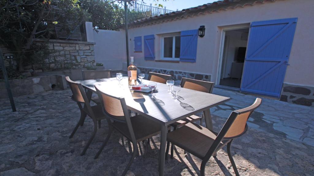 - une table en bois avec des chaises et une bouteille de vin dans l'établissement Villa Rico, à Sainte-Maxime