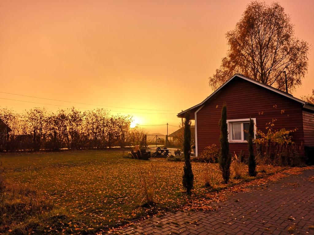 a house in a field with the sunset in the background at Gästehäuschen „kleine Auszeit“ in Greifswald