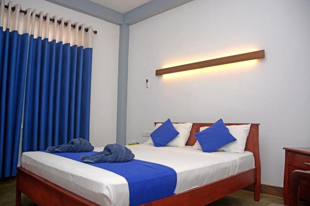 a bedroom with a bed with blue curtains at Hotel Thilon in Katunayake