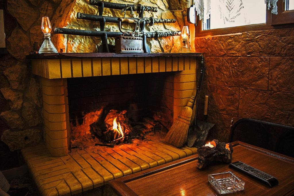 a brick fireplace with a fire in it at To Konaki in Synikia Mesi Trikalon