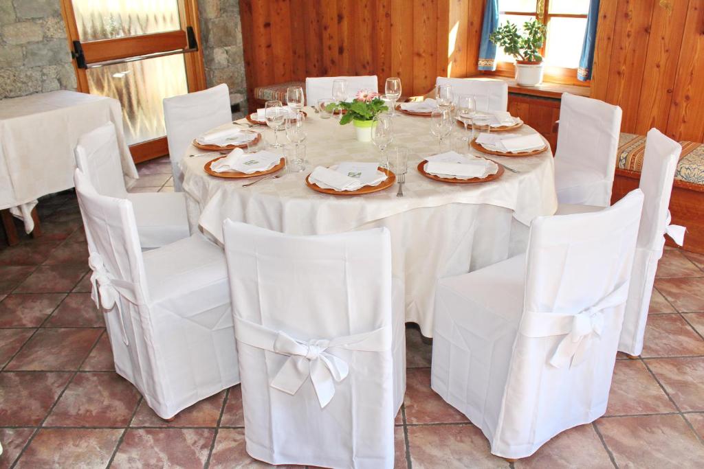 una sala da pranzo con tavolo e sedie bianche di Albergo Dei Pescatori a Piode