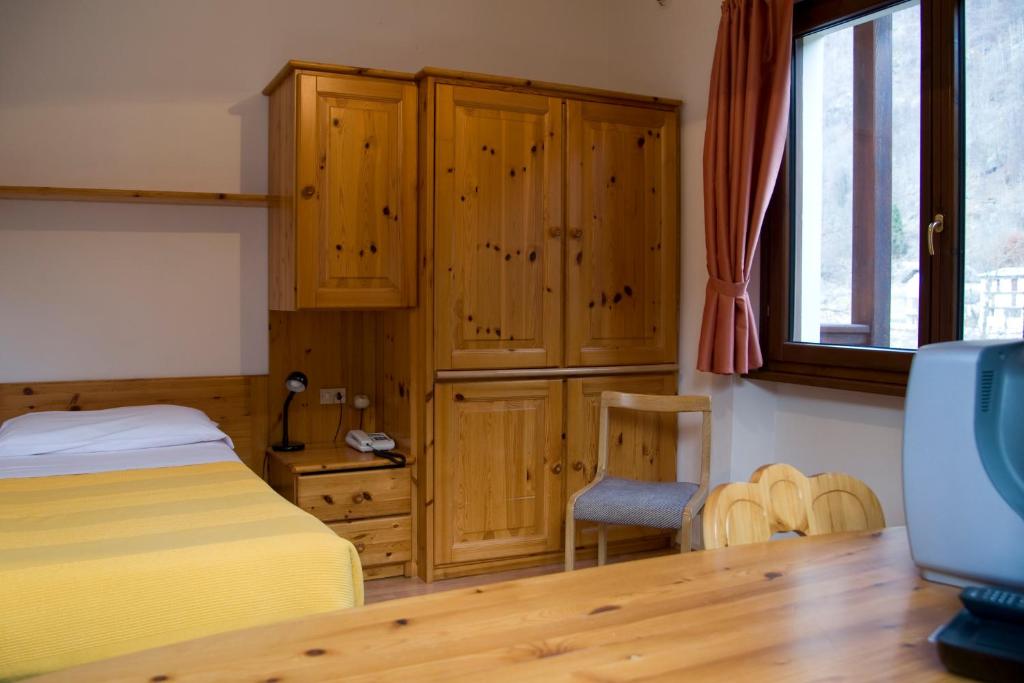 una camera con letto, armadi in legno e TV di Albergo Dei Pescatori a Piode