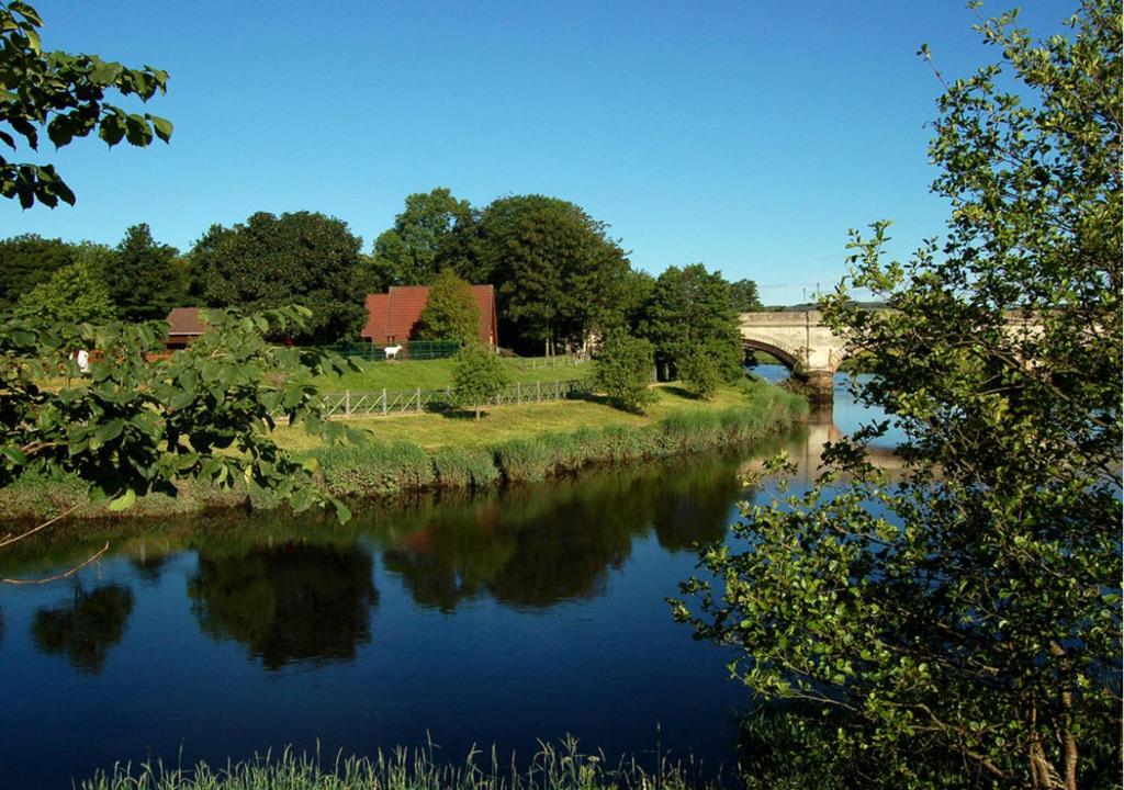 uma vista para um rio com uma ponte ao fundo em River Edge Lodges em Bridge of Earn