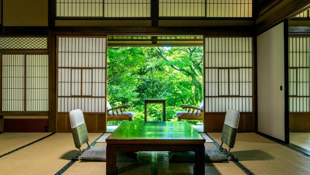 a dining room with a green table and chairs at Gora Kansuiro in Hakone