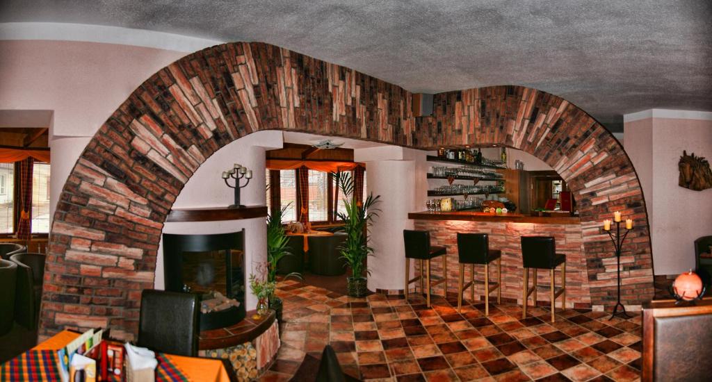 a living room with a brick fireplace and bar stools at Penzion Merlin in Frýdlant nad Ostravicí