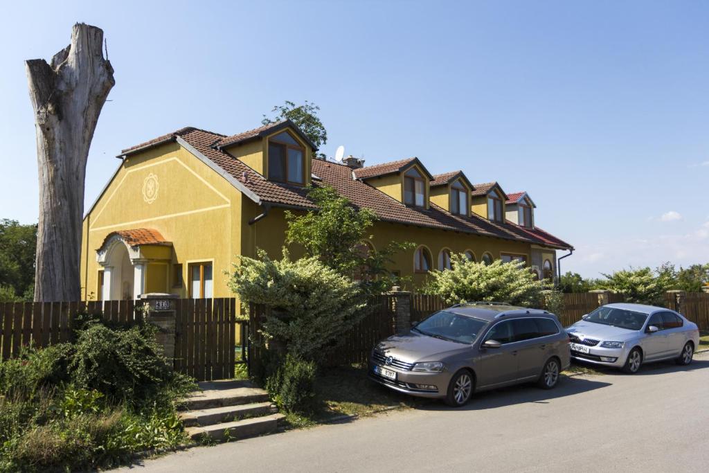 two cars parked in front of a yellow house at Penzion U maléřa in Hroznová Lhota