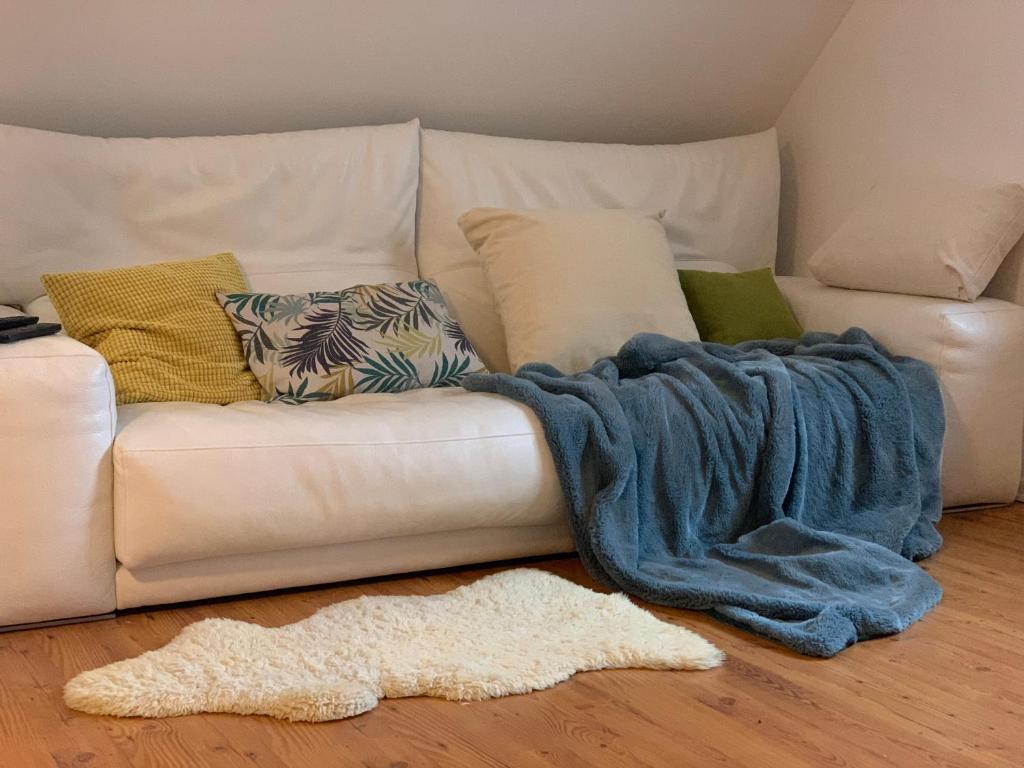 eine weiße Couch mit blauer Decke auf dem Boden in der Unterkunft Hinterhaus Apartment No1 in Leipzig
