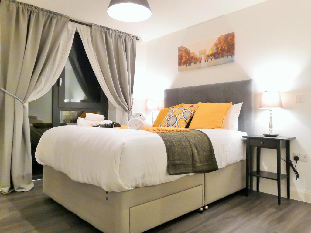 1 dormitorio con 1 cama grande con almohadas amarillas y naranjas en Comfy Birmingham City Center Apartment at Inge Street By HF Group, en Birmingham