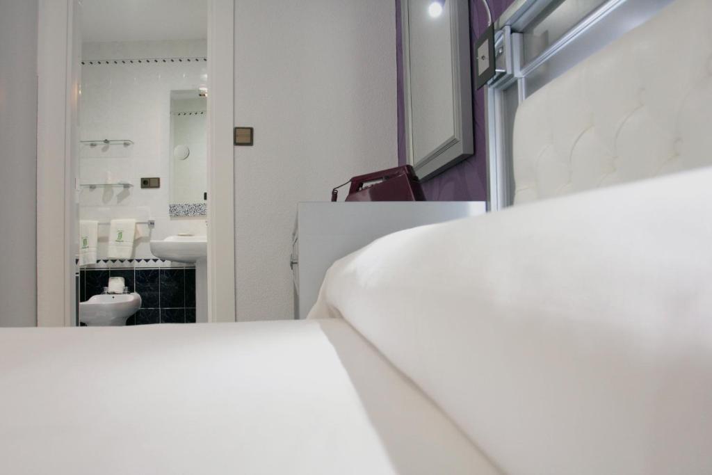 a bedroom with a white bed and a bathroom at Hotel Molinos in Granada