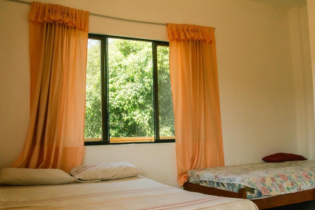 a bedroom with two beds and a large window at Hospedaje Costa Norte in Máncora