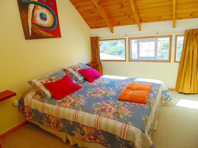 ein Schlafzimmer mit einem Bett mit bunten Kissen in der Unterkunft DEPARTAMENTOS CLIMENT in Osorno