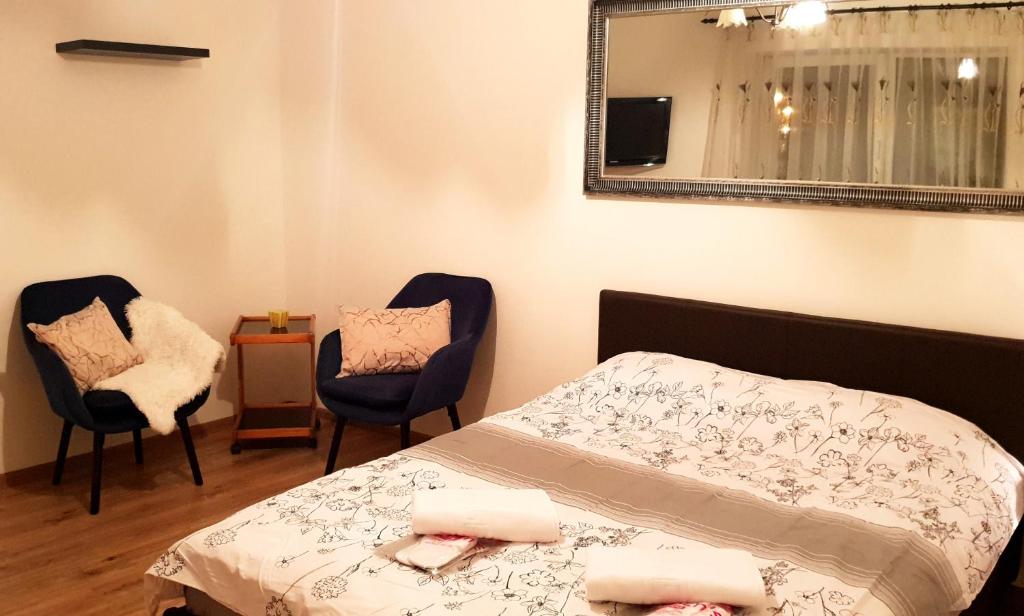 a bedroom with a bed and two chairs and a mirror at Central Apartment DumDix Brasov in Braşov
