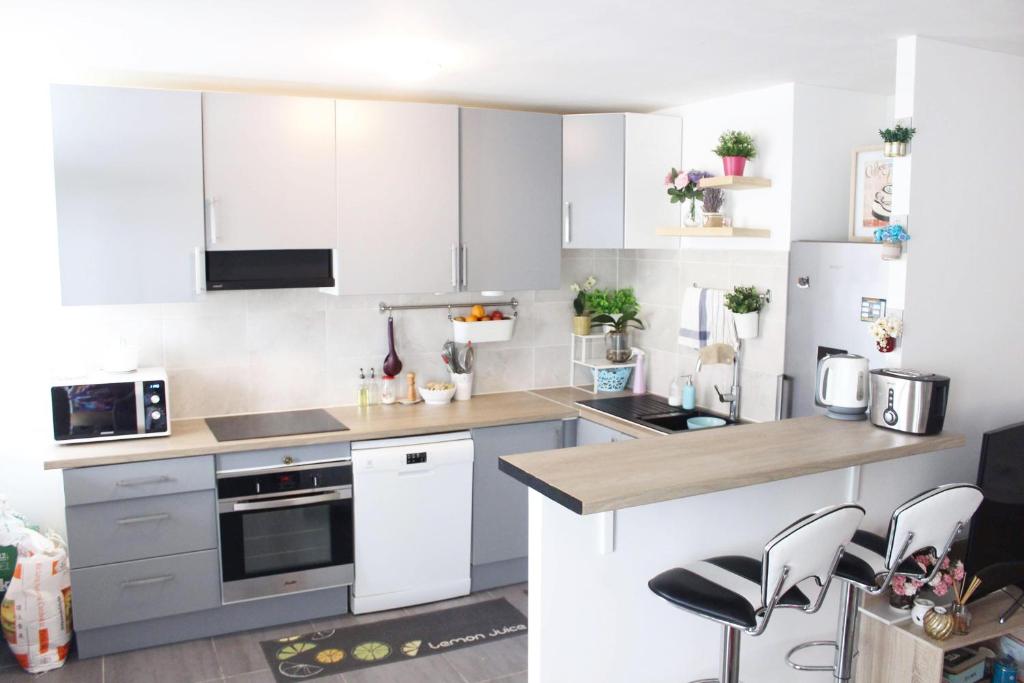 una cocina con armarios blancos y electrodomésticos blancos en Cosy 74m2 apartment close to Paris, en Houilles