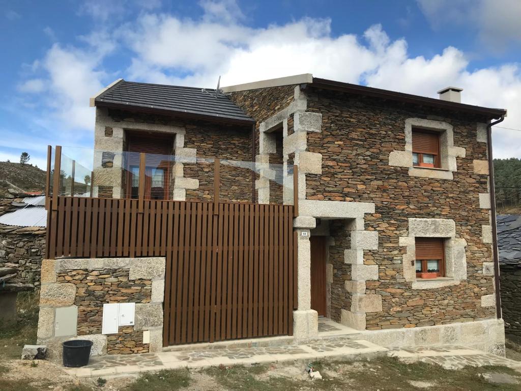 una casa de ladrillo con una valla de madera alrededor en Refúgio dos Macedos en Bilhó