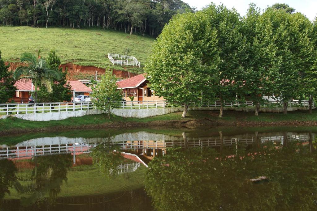 a pond with a house and trees and a fence at Fazenda Chico Pereira in Santo Antônio do Pinhal