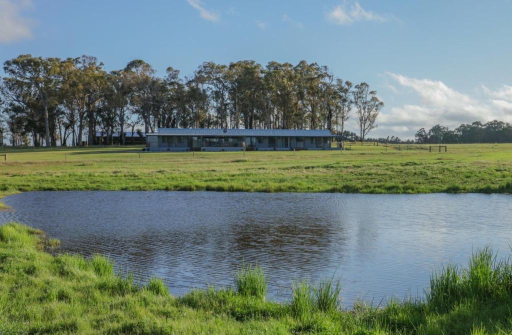 a building in a field next to a pond at Harmans Lodge Private Rural Escape in Wilyabrup