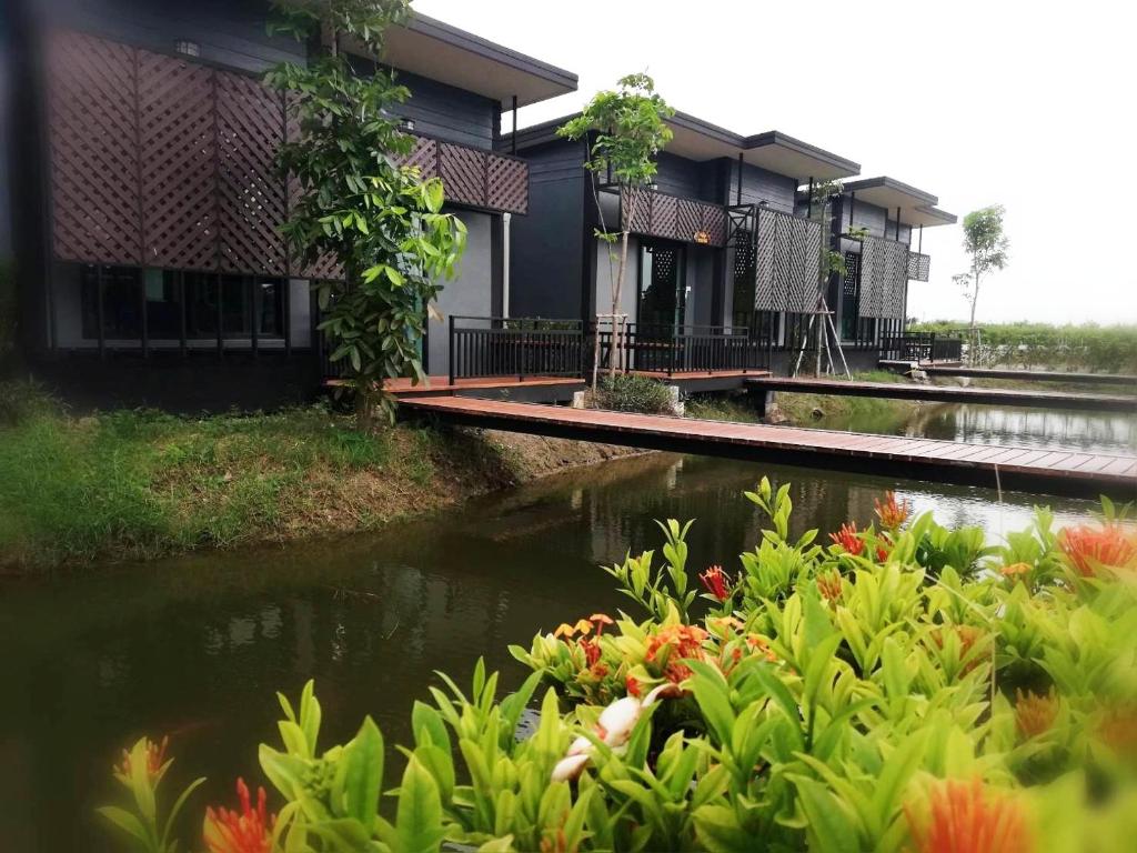 a row of houses next to a river with flowers at T'Luck House Resort in Haad Chao Samran