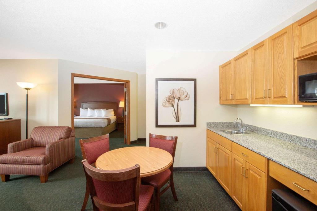a hotel room with a kitchen and a table and a bed at AmericInn by Wyndham Kearney in Kearney