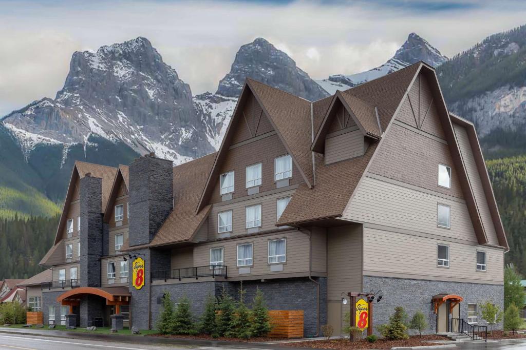 a large building with mountains in the background at Super 8 by Wyndham Canmore in Canmore